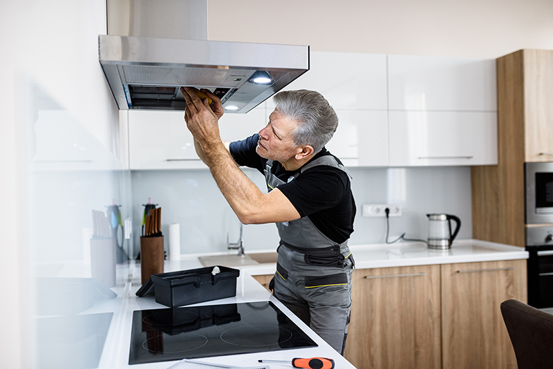 Engineer focused on appliance repair in a real kitchen